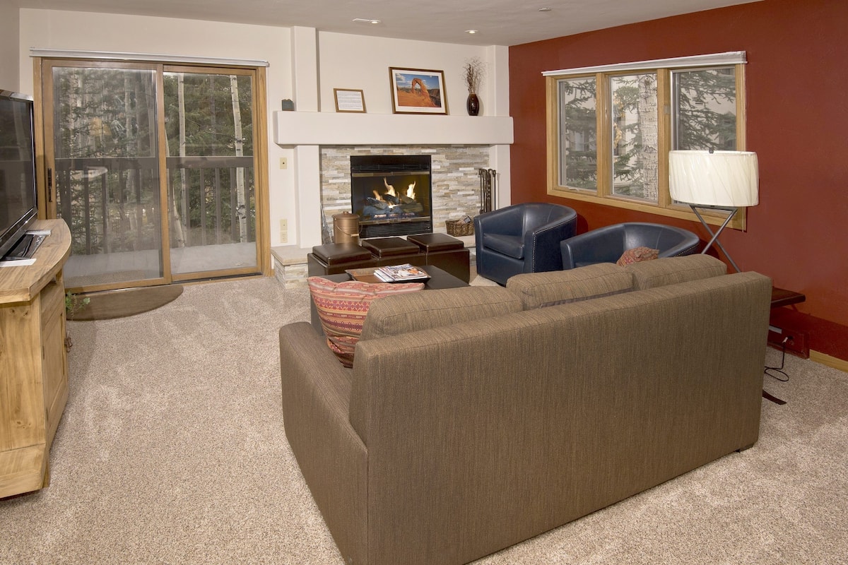 A living room with a fireplace, a television, and a large window.