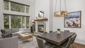 A spacious living room with a fireplace, large windows, and a dining area. - Edwards CO - Aspen Snowmasswood Lodge Vacation Rentals (Edwards)
