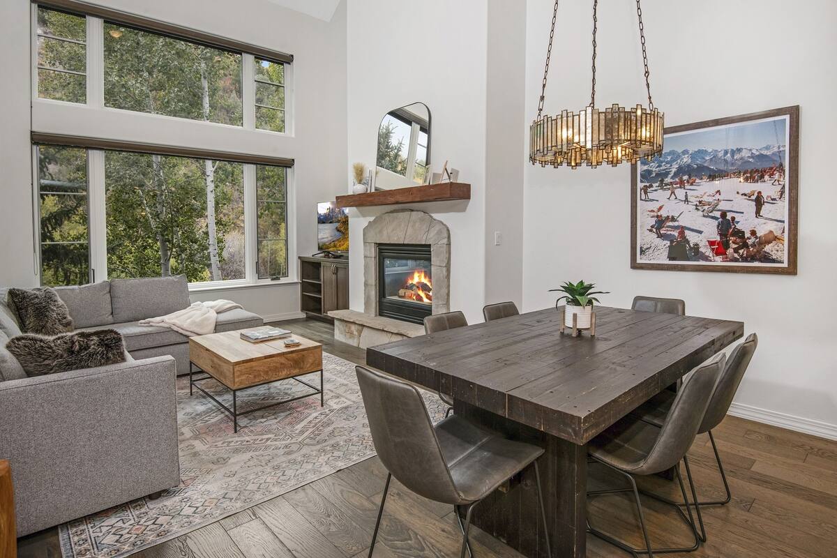 A spacious living room with a fireplace, large windows, and a dining area.