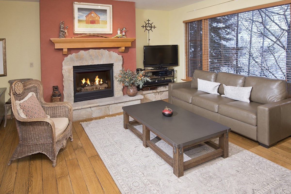 A living room with a fireplace, a sofa, a coffee table, and a television.