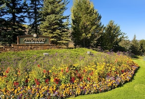 A sign for Arrowhead Country Club of the Rockies surrounded by a vibrant flower garden.