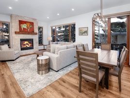 Una sala de estar moderna con chimenea, ventanas amplias y un comedor.
