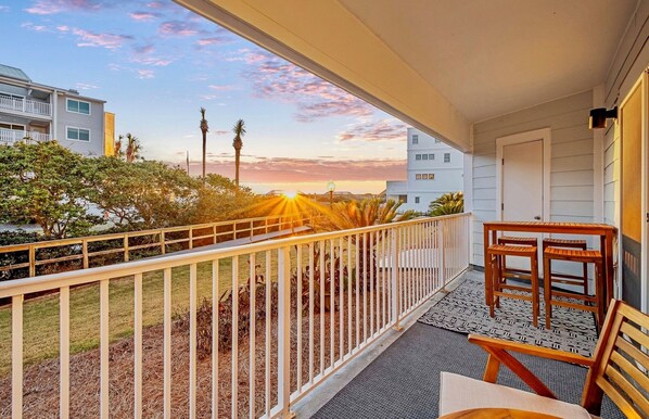 A balcony with a view of a sunset, a wooden table, and chairs. - New List 2BR/2BA - Gulf View Steps to Gulf Sleep 6 Full Renovation (Santa Rosa Beach)