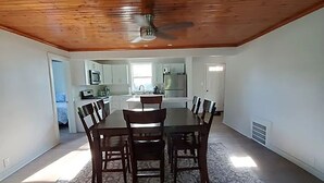 A spacious dining area with a wooden ceiling and a central table surrounded by chairs. - LakePointe Shores #9 Tranquil 3 bedroom cottage, enchanting Madison on the Lake (Madison)