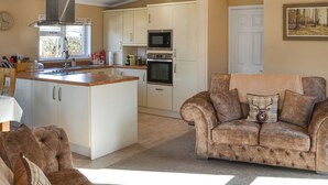 Een moderne keuken met een centraal eiland, witte kasten en roestvrijstalen apparatuur.