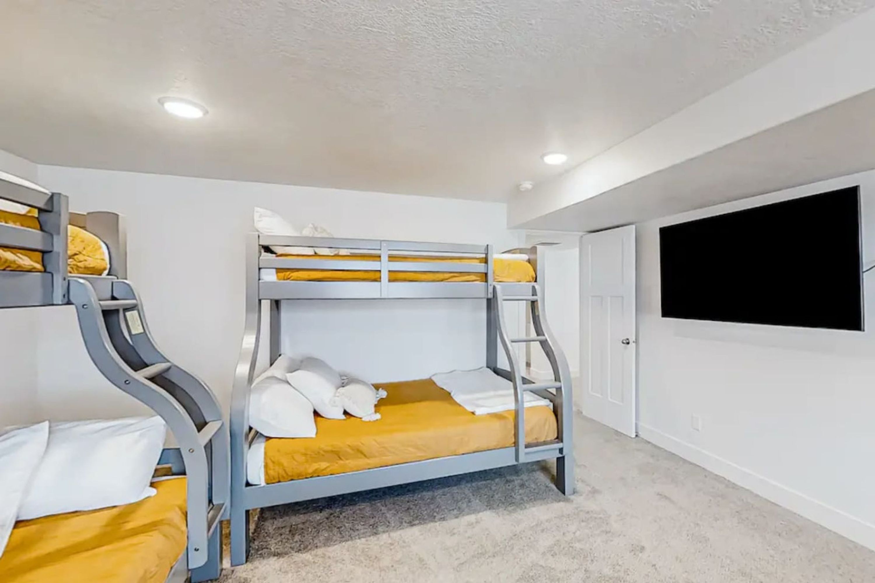 Camera con letto a castello e televisore a schermo piatto montato a parete.