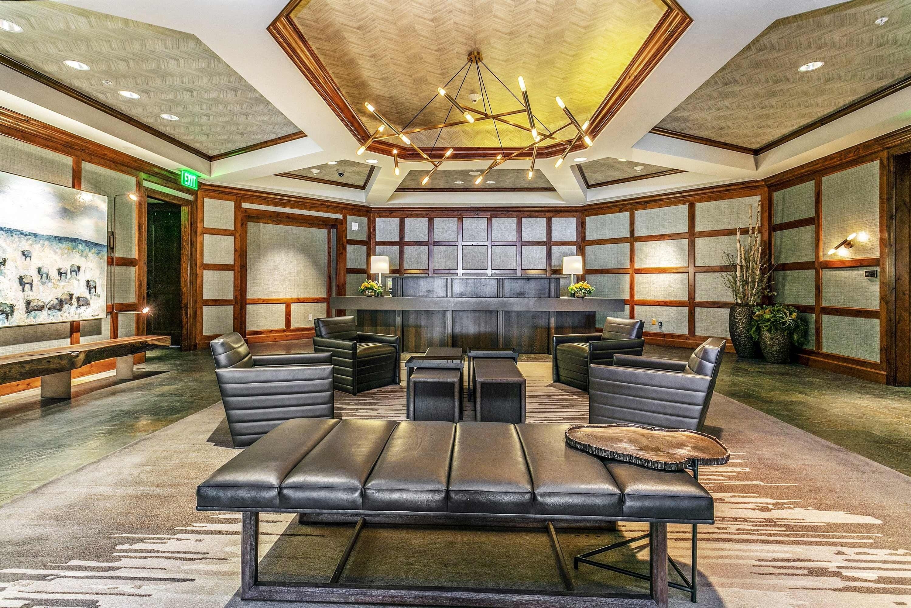 A lobby with leather seating, a reception desk, and a chandelier.