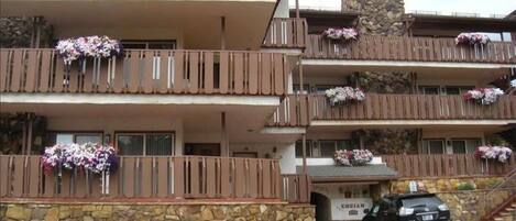 A multi-story hotel with balconies adorned with flowers, a stone facade, and a sign indicating the name 'ENZIAN'.