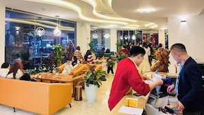Een moderne hotellobby met zithoeken, een receptiebalie en grote ramen met uitzicht op de stad.