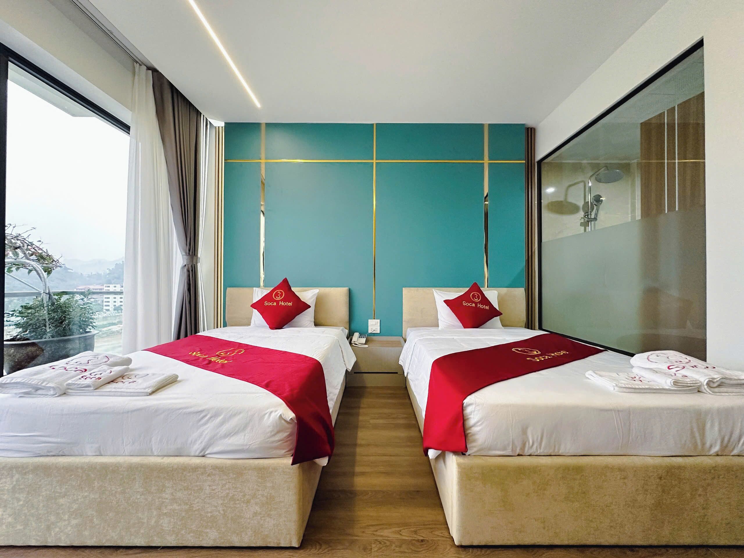 A hotel room with two beds, a large window, and a view of the city.