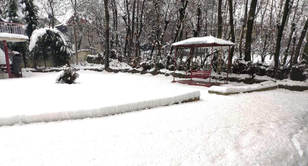 A snow-covered outdoor area with a gazebo and a bench.