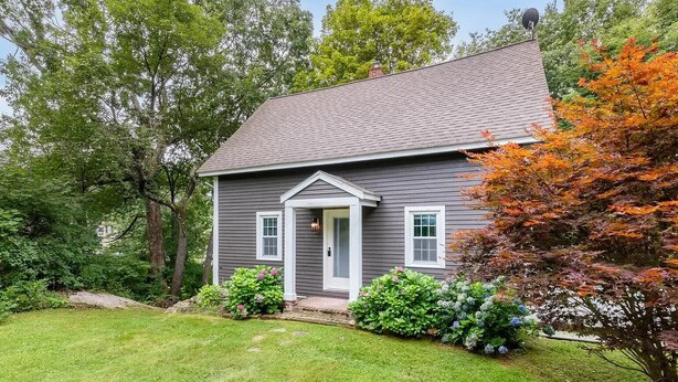 A two-story house with a grey exterior, a front porch, and a well-maintained lawn.
