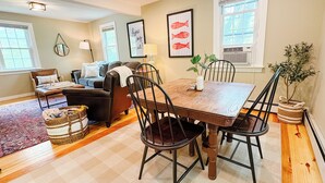 A dining area with a wooden table and chairs, a sofa, and a rug.