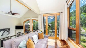 Un salon moderne avec une grande fenêtre, un canapé et un ventilateur de plafond.