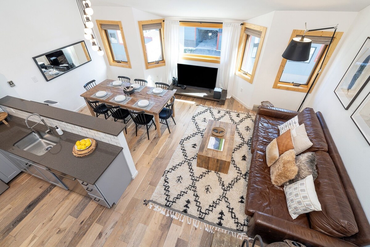 A modern kitchen with a dining area, a sofa, and a fireplace.