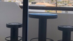 A balcony with three black tables and a view of mountains.