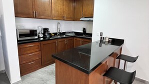 A modern kitchen with wooden cabinets, a black countertop, and a central island with bar stools.