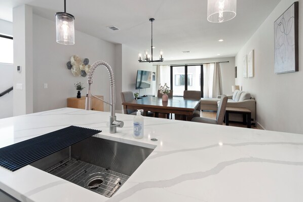 A modern kitchen with a central island, stainless steel sink, and pendant lighting.