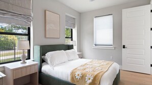 A bedroom with a bed, bedside table, lamp, and a window with blinds. - Luxury Home in North Austin: Next to Apple Campus (Austin)