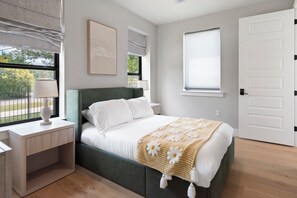 A bedroom with a bed, bedside table, lamp, and a window with blinds. - Luxury Home in North Austin: Next to Apple Campus (Austin)
