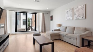 A modern living room with a sofa, a coffee table, and a TV. - Luxury Home in North Austin: Next to Apple Campus (Austin)