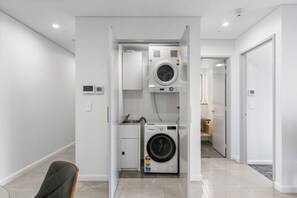 Een kleine wasruimte met een wasmachine, een droger en een klein wasbakje.