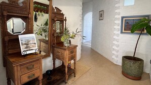 A room with a wooden dresser, a mirror, a framed picture, and a potted plant.