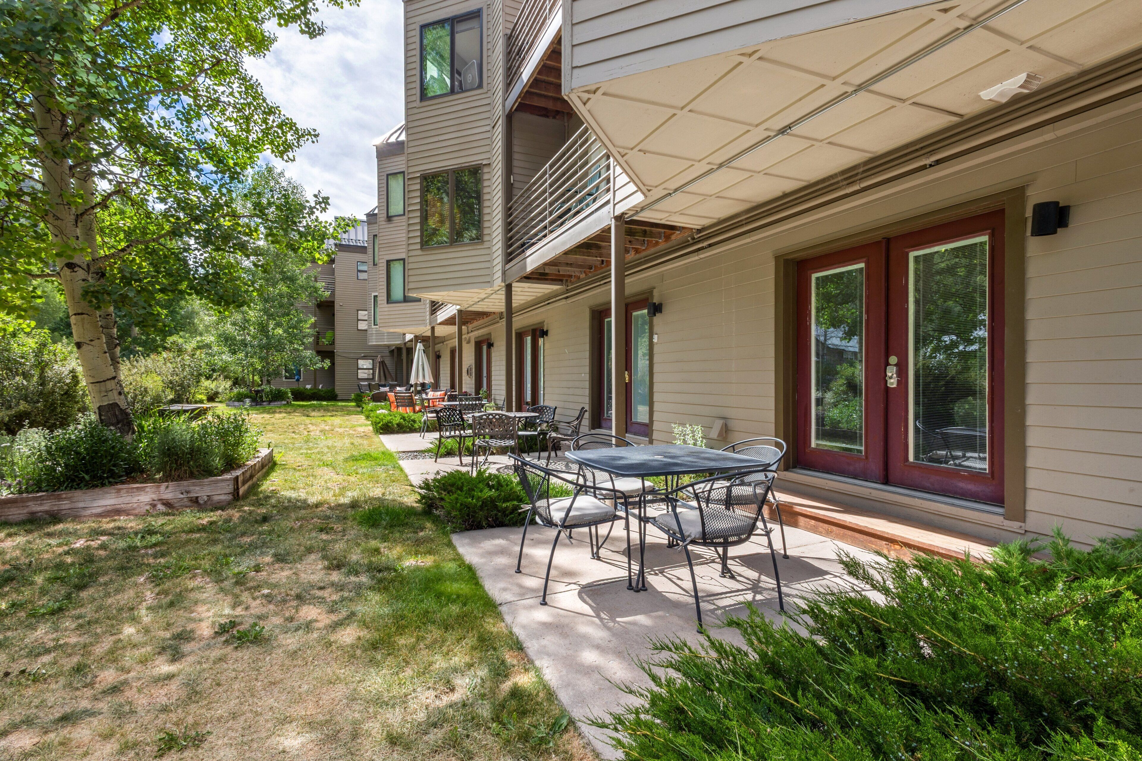 A modern building with a covered patio, outdoor seating, and a well-maintained garden.