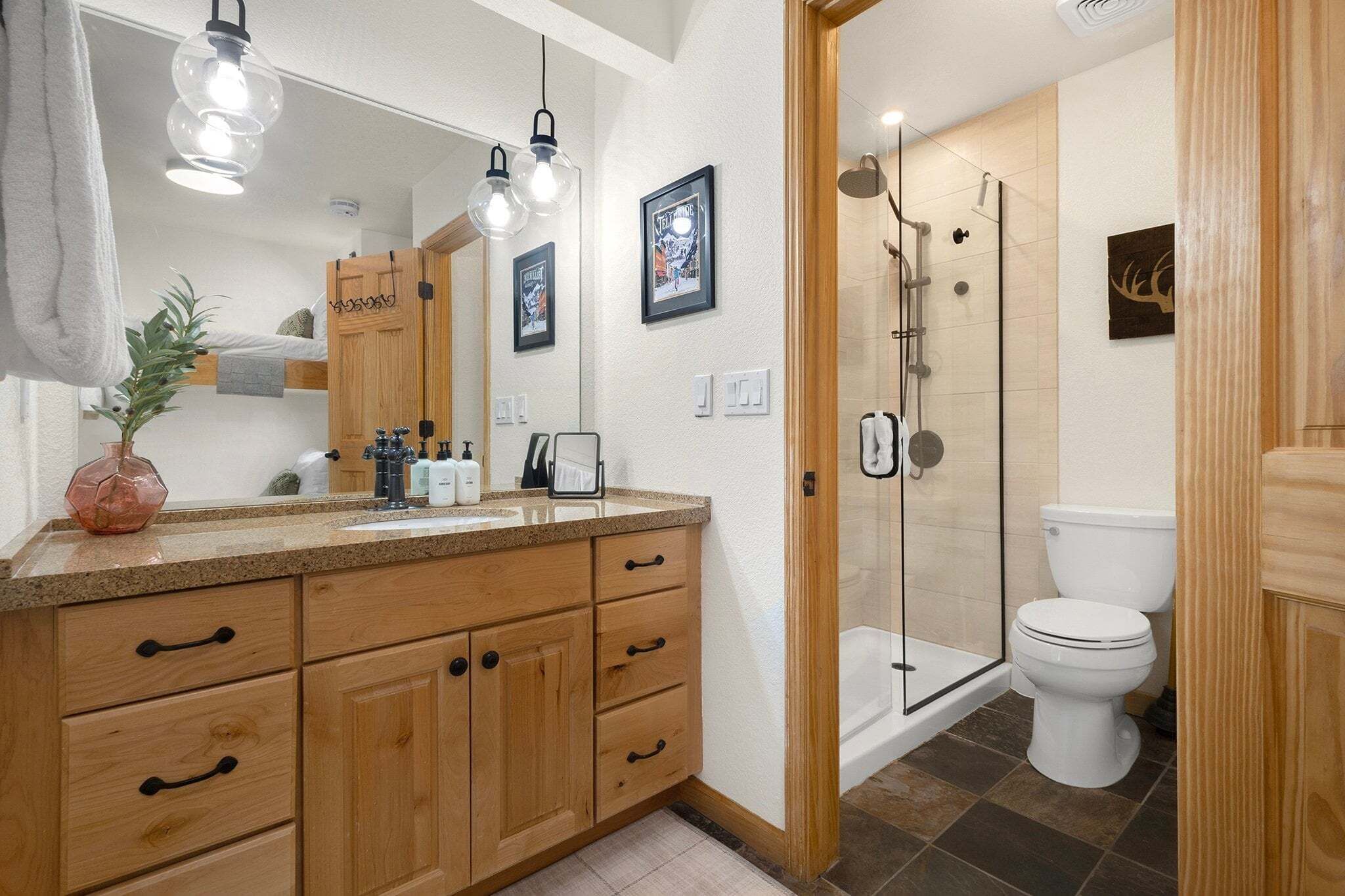 A modern bathroom with wooden cabinets, a large mirror, and a shower area.