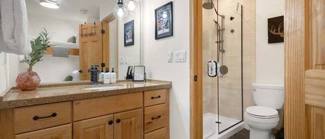 A modern bathroom with wooden cabinets, a large mirror, and a shower area.