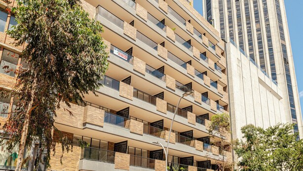 A multi-story building with a ground-level commercial space, large windows, and a visible balcony on the second floor. - Loft with unique view of the Center and Monserrate (Bogotá)