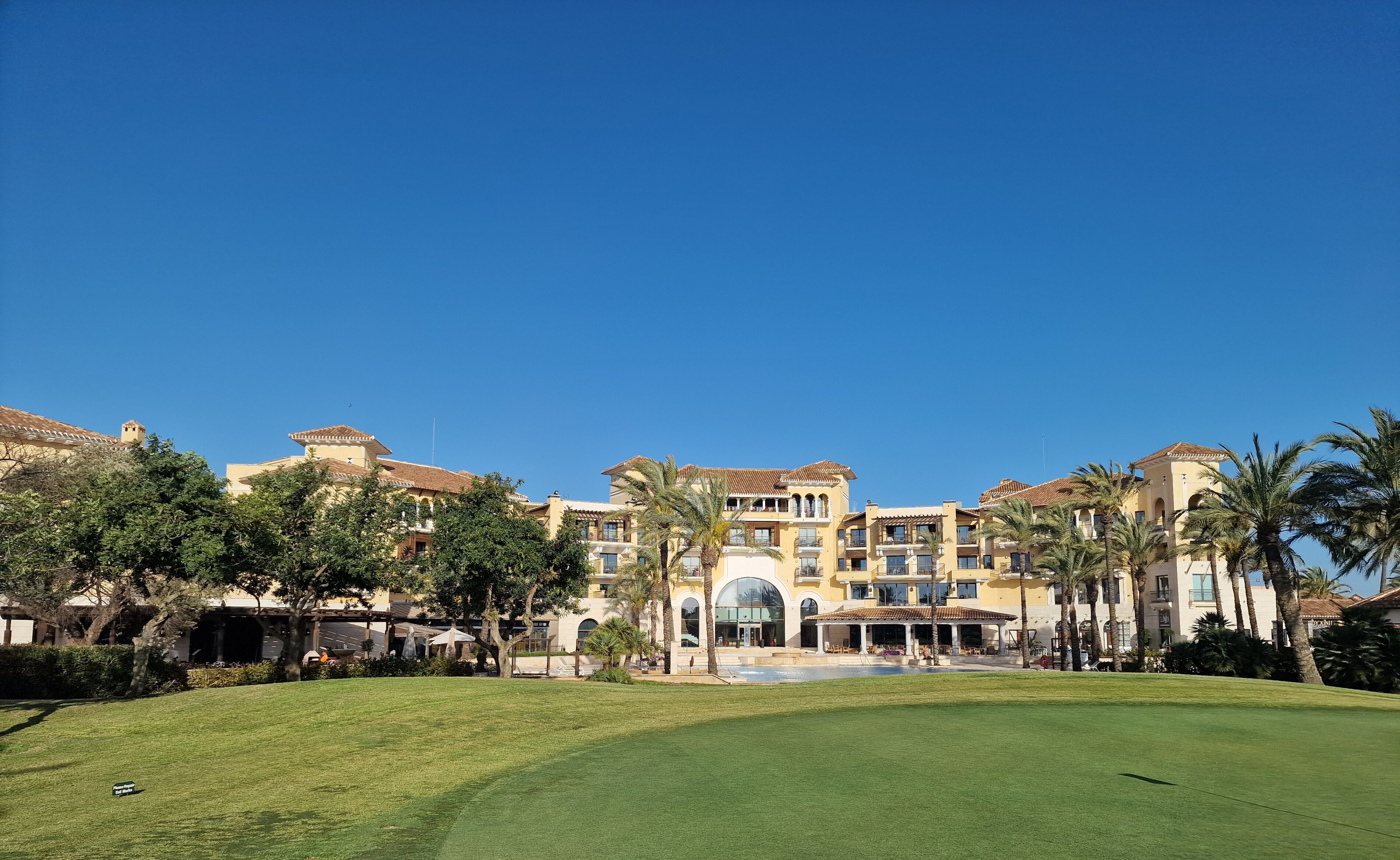 A hotel with multiple floors, a central courtyard, and palm trees.