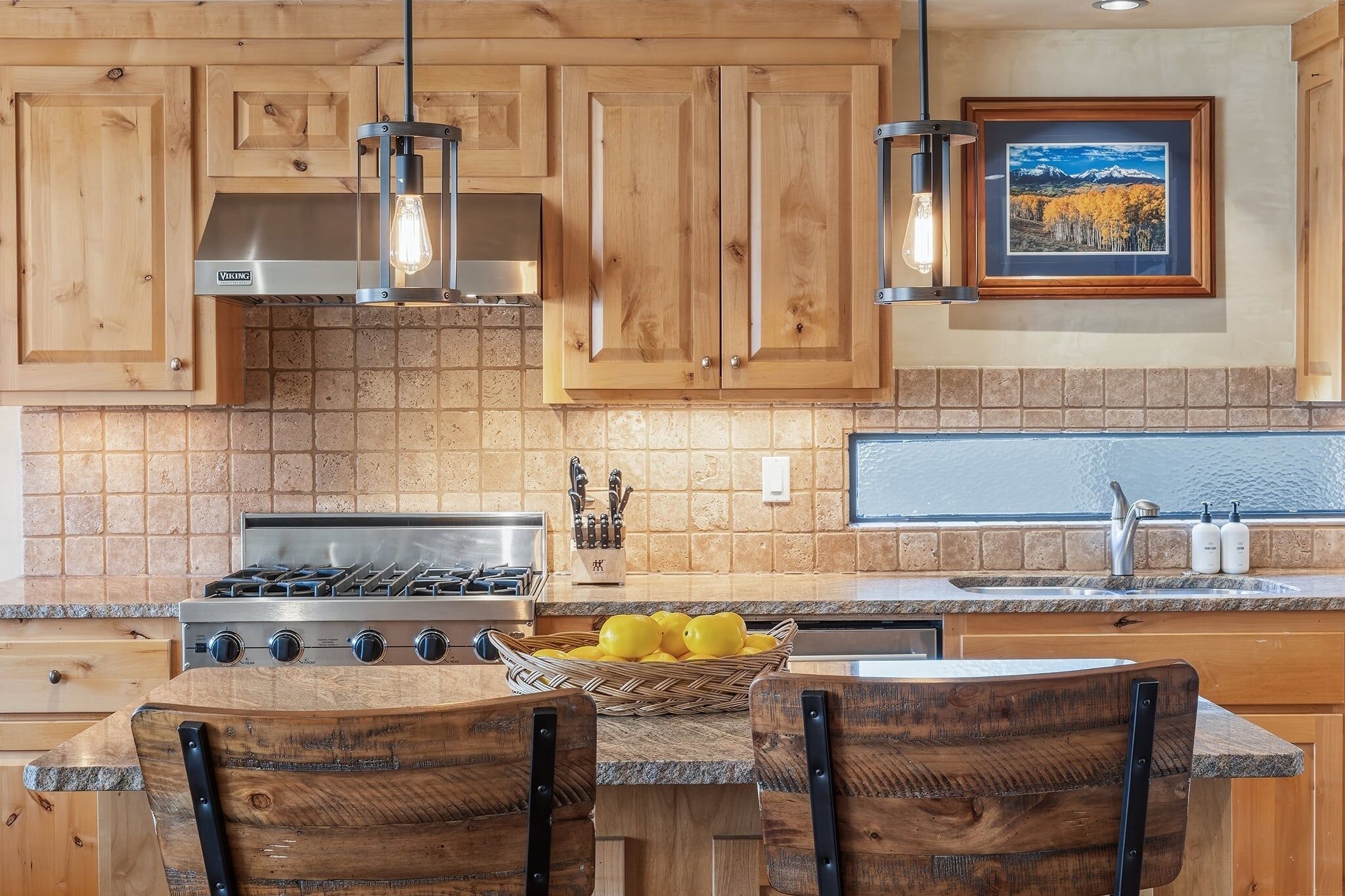 A kitchen with wooden cabinets, a gas stove, a sink, and a framed picture on the wall.