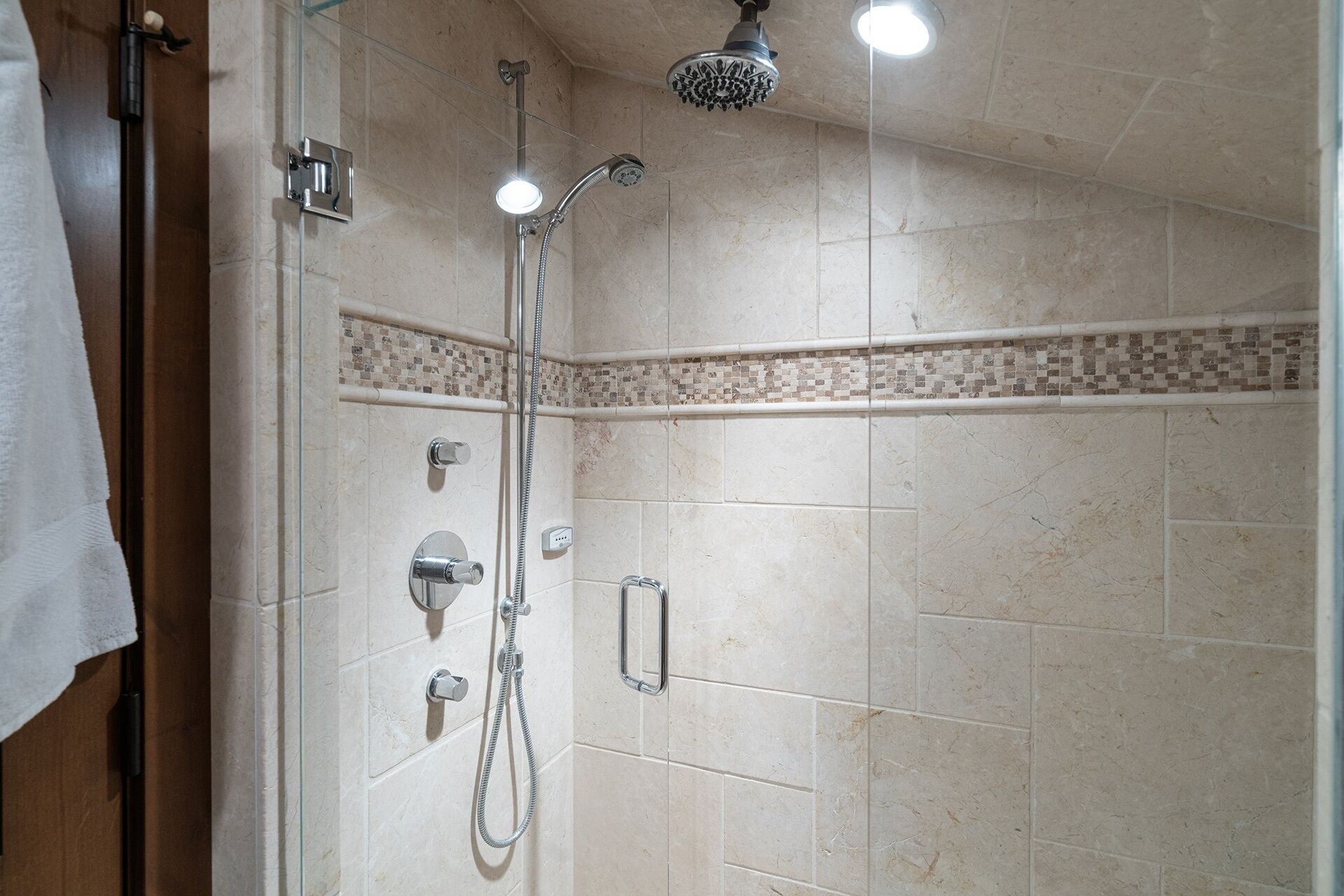 A shower with a handheld showerhead and a wall-mounted faucet.