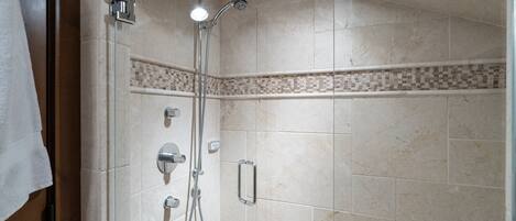 A shower with a handheld showerhead and a wall-mounted faucet.