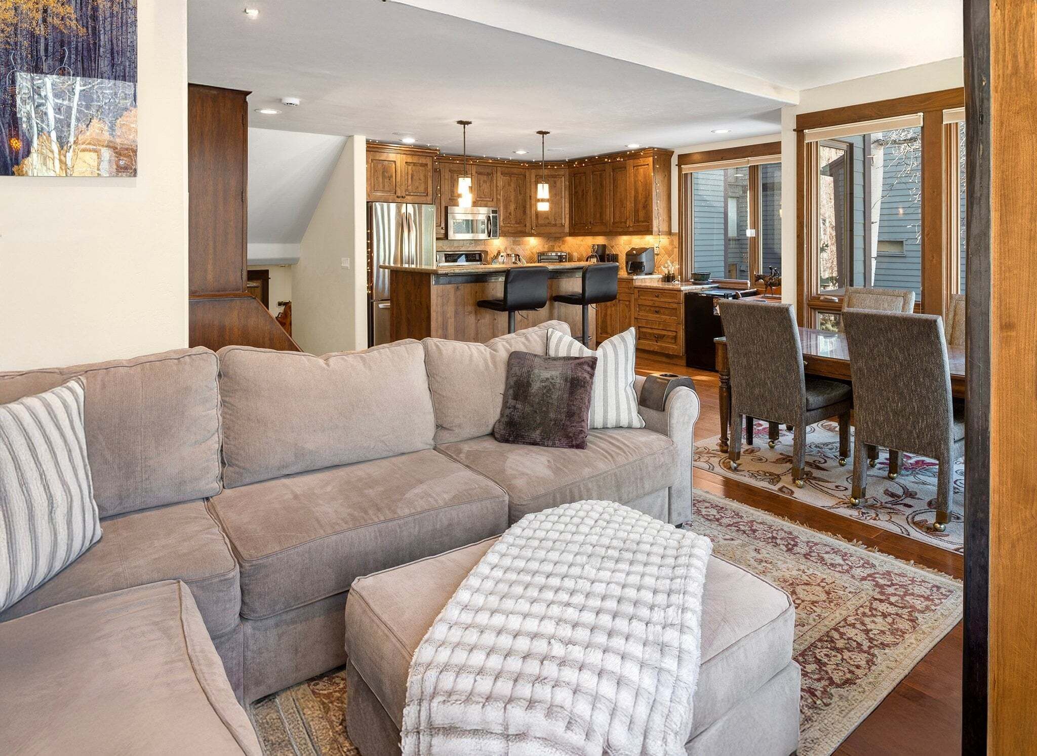 Una sala moderna con sofá, reposapiés y una zona de comedor con sillas y una mesa.
