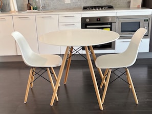 Une cuisine moderne avec des meubles blancs, un lave-vaisselle Bosch, une cuisinière et un four à micro-ondes.