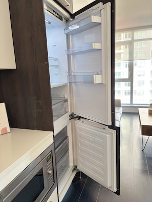 A modern kitchen with a built-in refrigerator, a microwave, and a wooden cabinet.