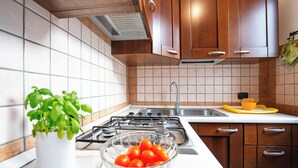 Una cocina con gabinetes de madera, una estufa a gas, un lavamanos y un tazón de tomates.