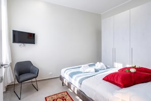 Une chambre à coucher avec un lit, une chaise, une télévision et une armoire.