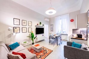 Un salon moderne comprenant un canapé, un fauteuil, une table à manger et un téléviseur.