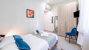 Ein modernes Schlafzimmer mit einem Bett, einem Sessel, einem Fernseher und einem Spiegel.