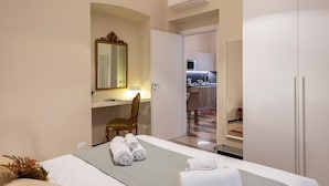A hotel room with a bed, a desk, a chair, a mirror, and a kitchenette in the background. - Lovely Apartment In Genova Historic Center A/C A, Genova, Italy (Genova)