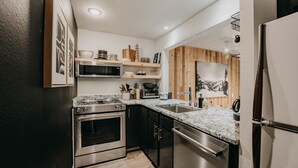 A modern kitchen with stainless steel appliances, wooden accents, and a marble countertop. - Glacier WA Mt Baker Vacation Rentals (Deming)