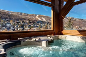 Un jacuzzi con vistas a una montaña nevada y un pueblo.