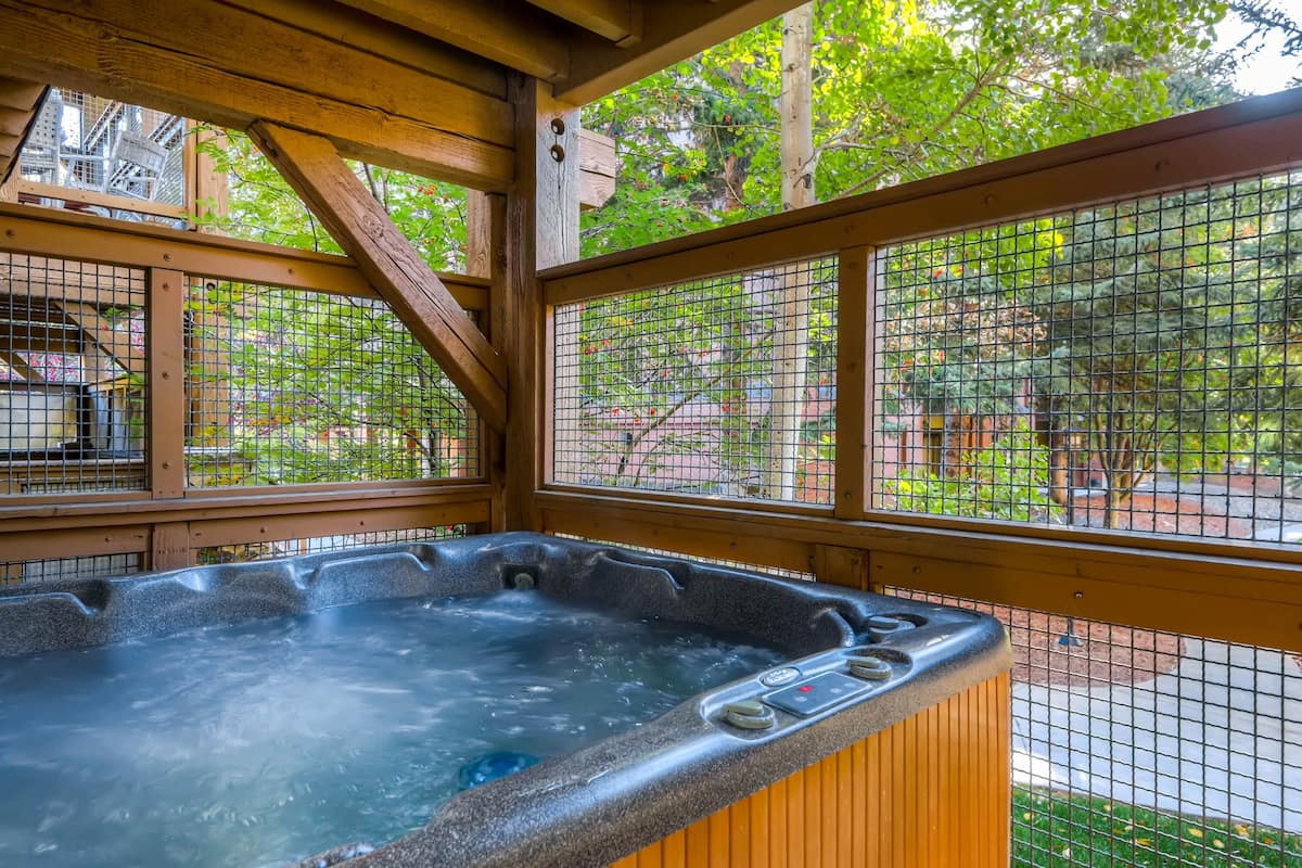 Ein Whirlpool in einer Holzkonstruktion mit Blick auf einen Garten und Bäume.