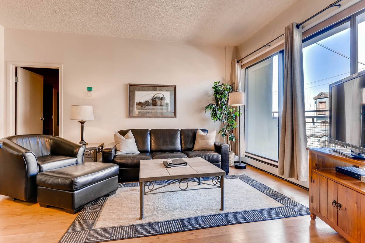 A modern living room with a leather sofa, a coffee table, and a TV on a wooden cabinet.
