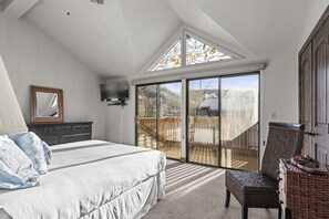 A bedroom with a large bed, a dresser, a television, and a balcony with a view of the outdoors. - Park City Ski Resort Resort Vacation Homes (Park City)