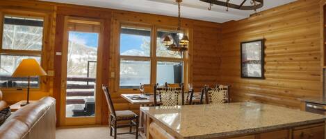 Interior de una cabaña de troncos con cocina, comedor y una zona de estar acogedora.