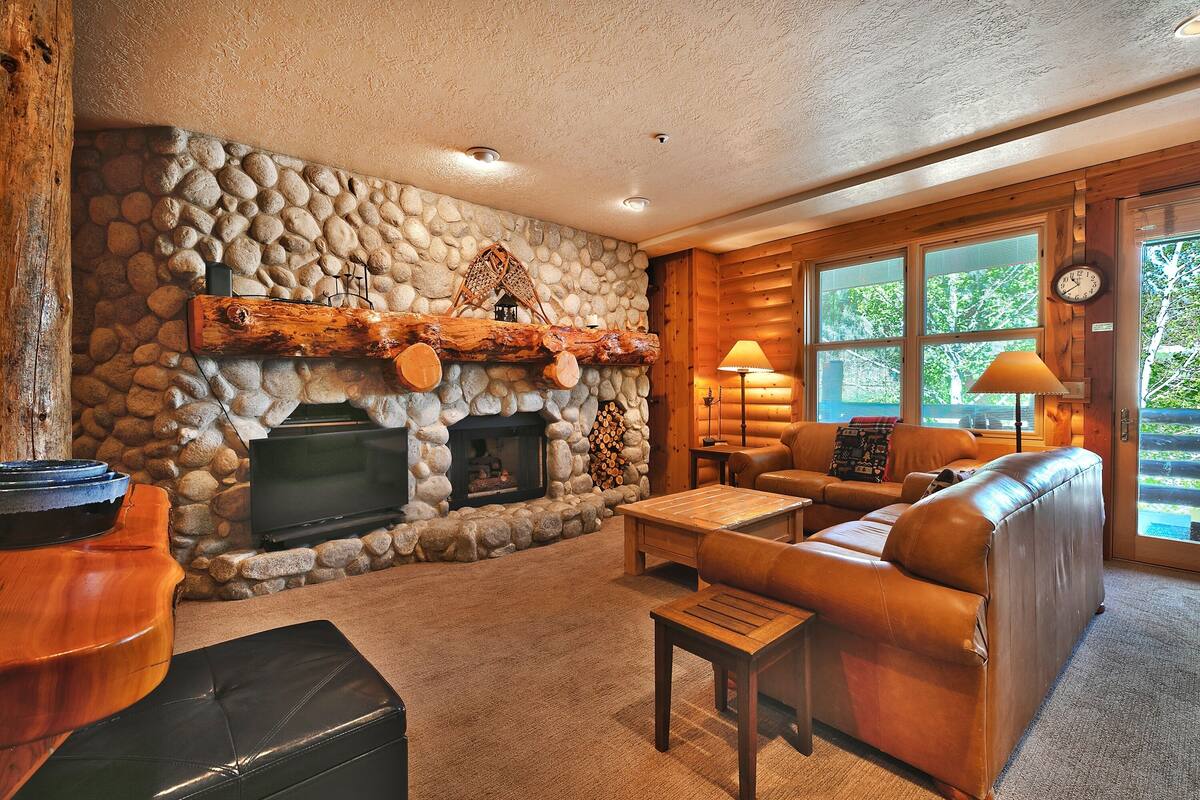 A cozy living room with a stone fireplace, leather sofa, and a television.